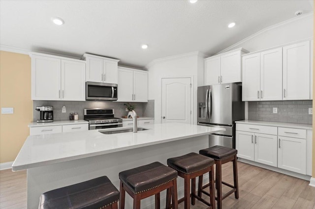 kitchen with sink, stainless steel appliances, white cabinets, and a center island with sink