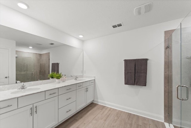 bathroom featuring hardwood / wood-style flooring, vanity, and a shower with door