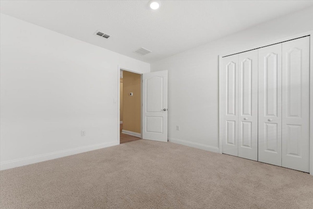 unfurnished bedroom featuring light carpet and a closet