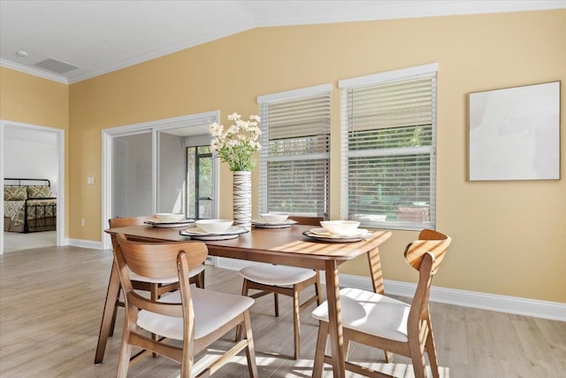 dining space with lofted ceiling, ornamental molding, and light wood-type flooring