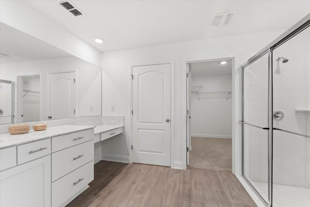 bathroom with hardwood / wood-style flooring, vanity, and an enclosed shower