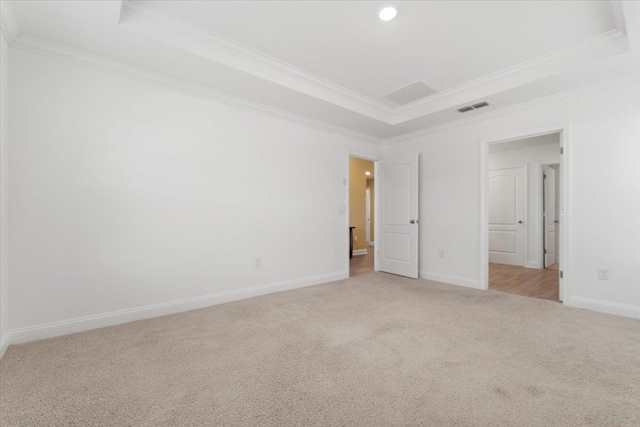 carpeted spare room with ornamental molding and a tray ceiling