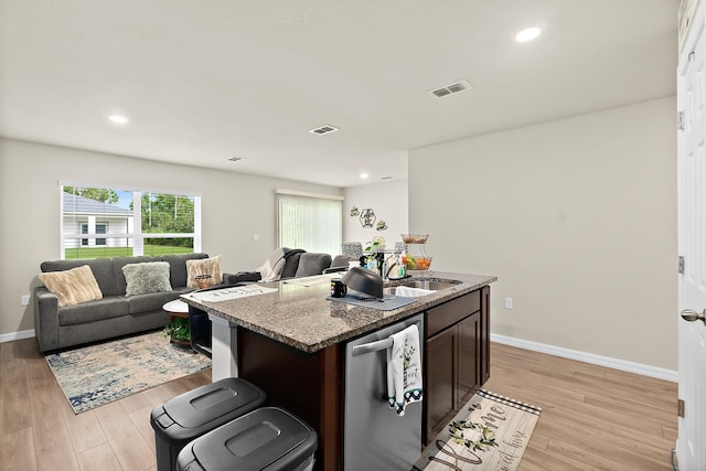 kitchen featuring dishwasher, stone counters, a center island with sink, light hardwood / wood-style flooring, and dark brown cabinets