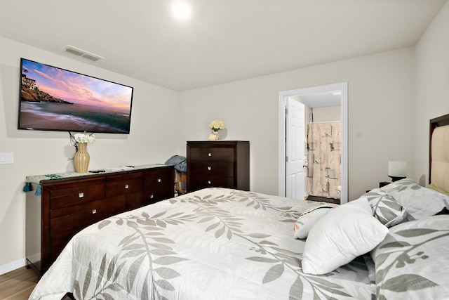 bedroom with hardwood / wood-style flooring and ensuite bath