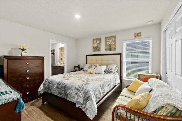 bedroom featuring a closet, connected bathroom, and light hardwood / wood-style flooring