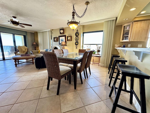 tiled dining room featuring ceiling fan, plenty of natural light, and a textured ceiling