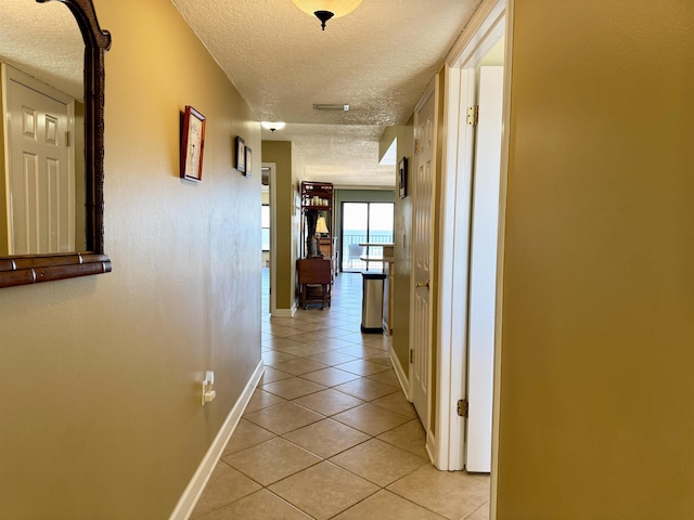 hallway featuring light tile patterned floors and a textured ceiling