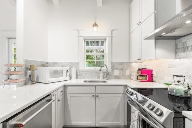 48 Osceola St, Saint Augustine, FL 32084 - kitchen with a sink, white cabinetry, backsplash, wall chimney range hood, and appliances with stainless steel finishes