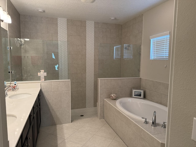 full bath with a garden tub, tile patterned flooring, a textured ceiling, and a sink