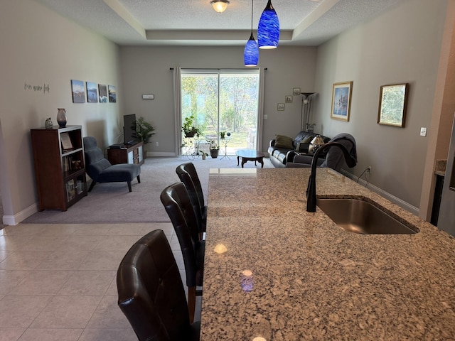 kitchen with light tile patterned floors, a textured ceiling, a sink, and pendant lighting