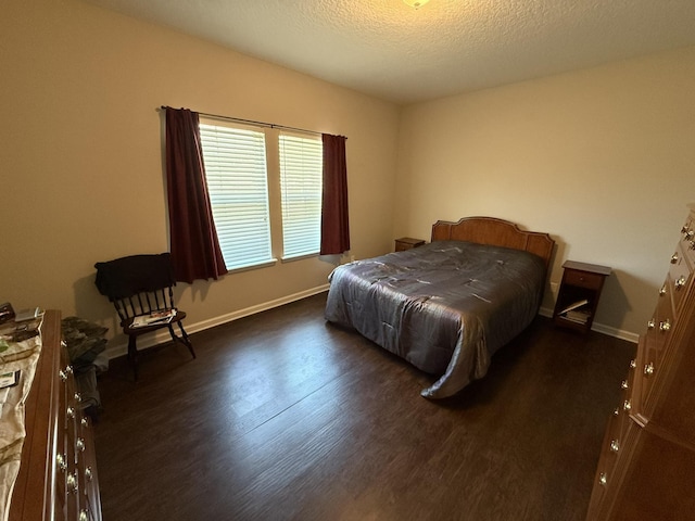 bedroom with a textured ceiling, baseboards, and wood finished floors