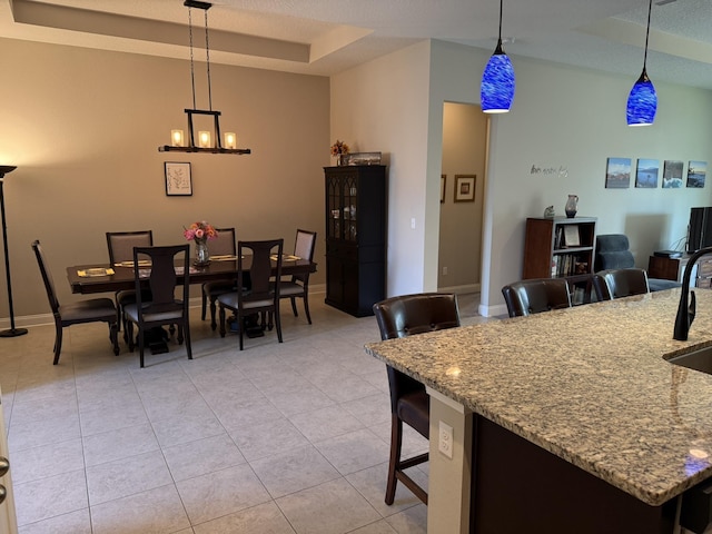 dining space with light tile patterned floors, a tray ceiling, a textured ceiling, and baseboards