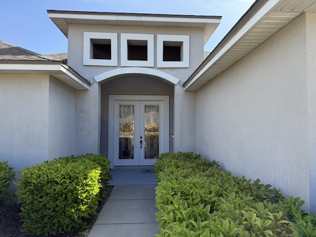 doorway to property with french doors, roof with shingles, and stucco siding