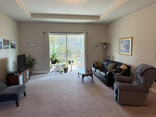 living room featuring a textured ceiling, a tray ceiling, and carpet flooring