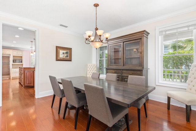 dining space featuring dark hardwood / wood-style floors, crown molding, and a notable chandelier