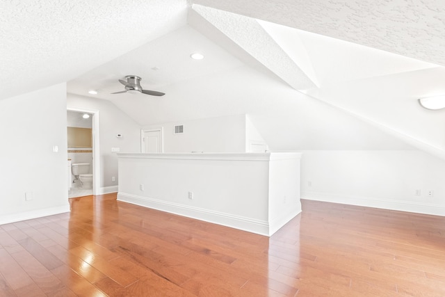 bonus room featuring a textured ceiling, hardwood / wood-style flooring, vaulted ceiling, and ceiling fan