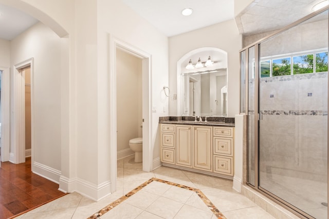 bathroom featuring hardwood / wood-style floors, vanity, a shower with door, and toilet