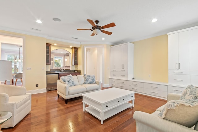 living room featuring ceiling fan, ornamental molding, and light hardwood / wood-style flooring