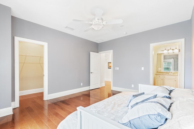 bedroom with ensuite bath, ceiling fan, a spacious closet, hardwood / wood-style floors, and a closet