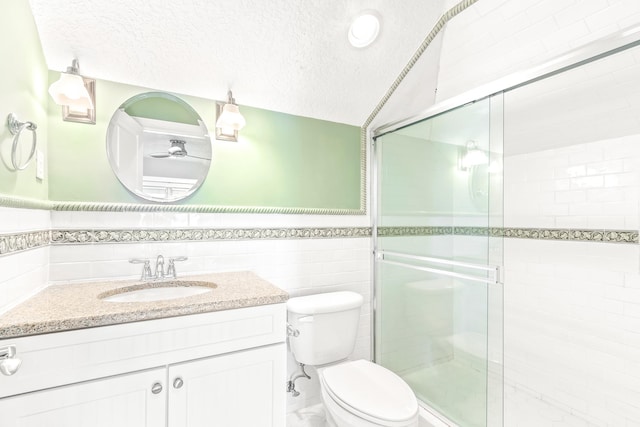 bathroom featuring a textured ceiling, an enclosed shower, toilet, vanity, and tile walls