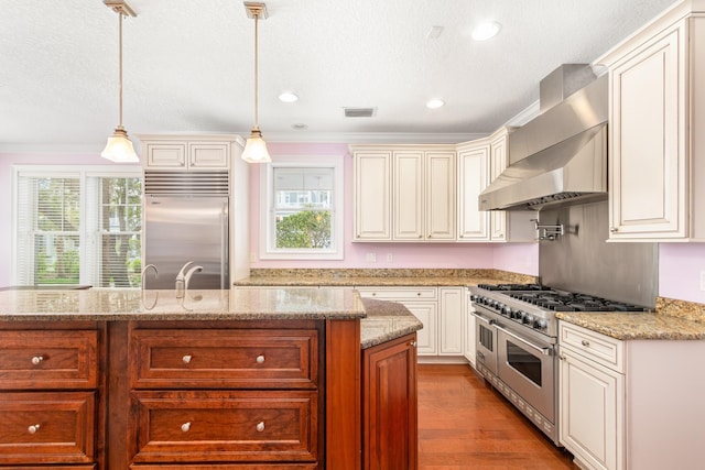 kitchen with wall chimney exhaust hood, light stone counters, pendant lighting, high quality appliances, and light wood-type flooring