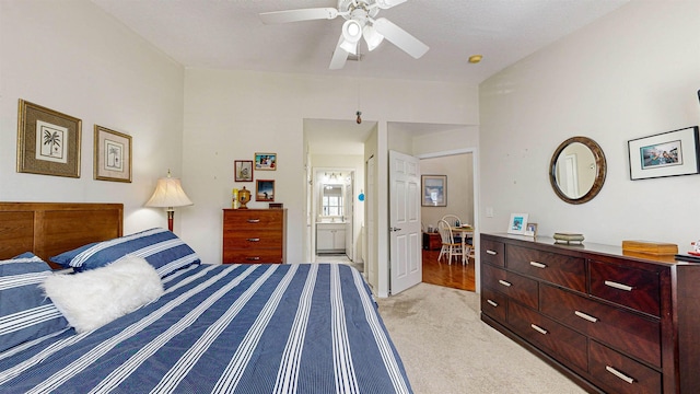 bedroom with ceiling fan, light colored carpet, and connected bathroom