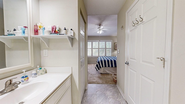 bathroom with a textured ceiling, vanity, and ceiling fan