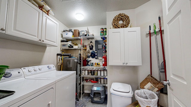 washroom with washing machine and clothes dryer, cabinets, and a textured ceiling