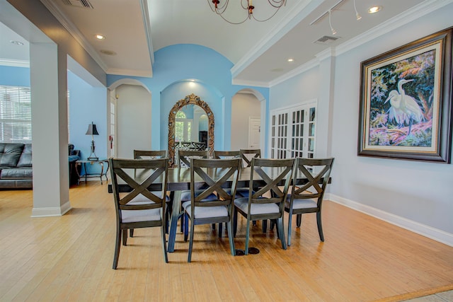 dining area with ornamental molding, a notable chandelier, and light wood-type flooring