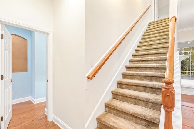 stairs with ornamental molding and hardwood / wood-style flooring