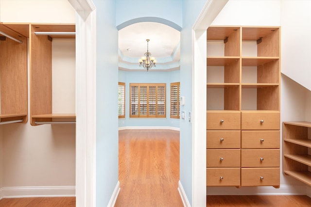 spacious closet featuring light hardwood / wood-style floors and a notable chandelier