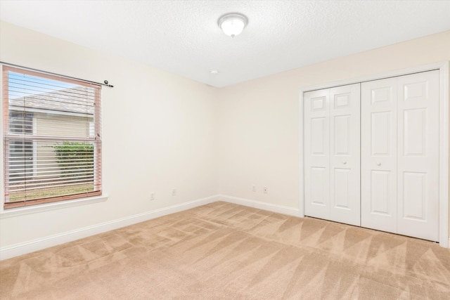 unfurnished bedroom with carpet flooring, a textured ceiling, and a closet