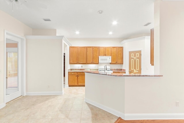 kitchen featuring ceiling fan, sink, light stone counters, kitchen peninsula, and light tile patterned floors