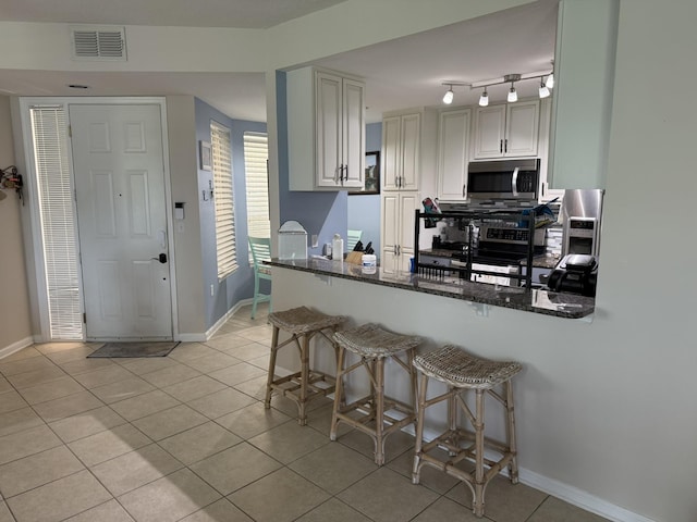 1810 Prestwick Pl, Saint Augustine, FL 32086 - kitchen with stainless steel appliances, light tile patterned floors, dark stone countertops, and a kitchen breakfast bar