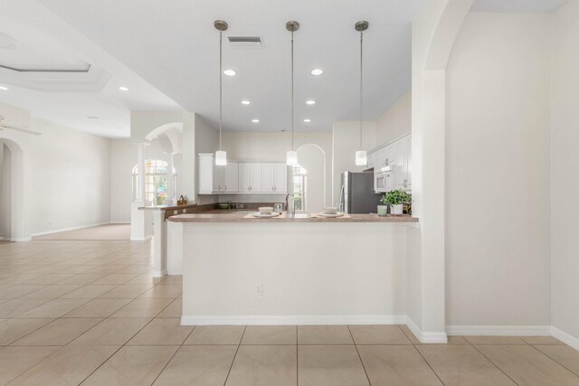 19 Ehrling Ln, Palm Coast, FL 32164 - kitchen with freestanding refrigerator, arched walkways, white cabinets, a peninsula, and recessed lighting