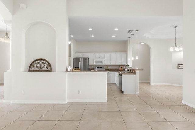 19 Ehrling Ln, Palm Coast, FL 32164 - kitchen featuring stainless steel appliances, a peninsula, white cabinets, arched walkways, and recessed lighting
