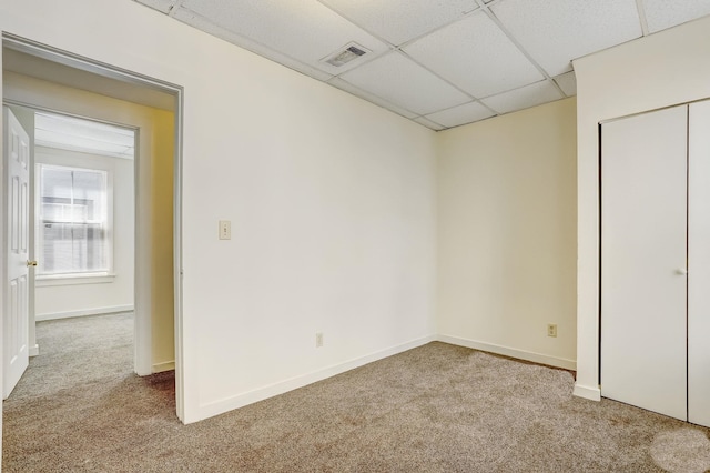 spare room with a drop ceiling and light colored carpet