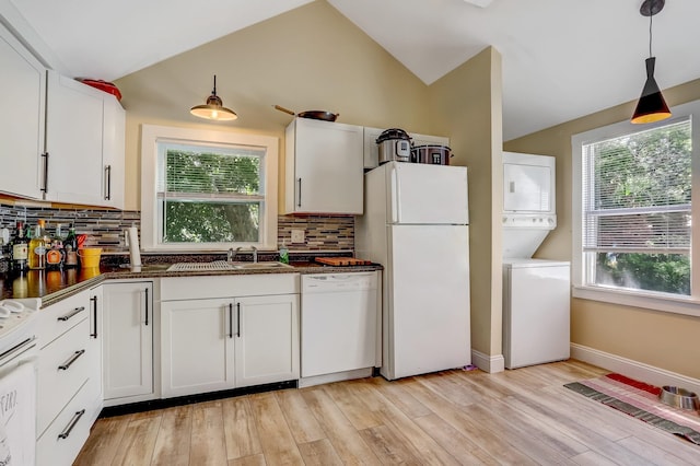 kitchen featuring white appliances, stacked washer / drying machine, sink, and white cabinets