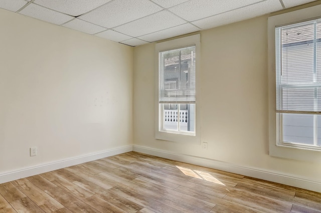 unfurnished room with a drop ceiling and light wood-type flooring