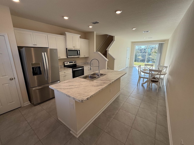 kitchen with stainless steel appliances, sink, a center island with sink, and white cabinets