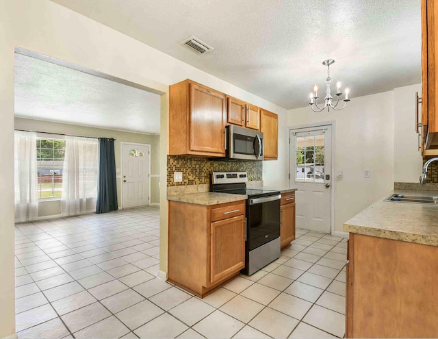 kitchen featuring a healthy amount of sunlight, sink, stainless steel appliances, and a chandelier