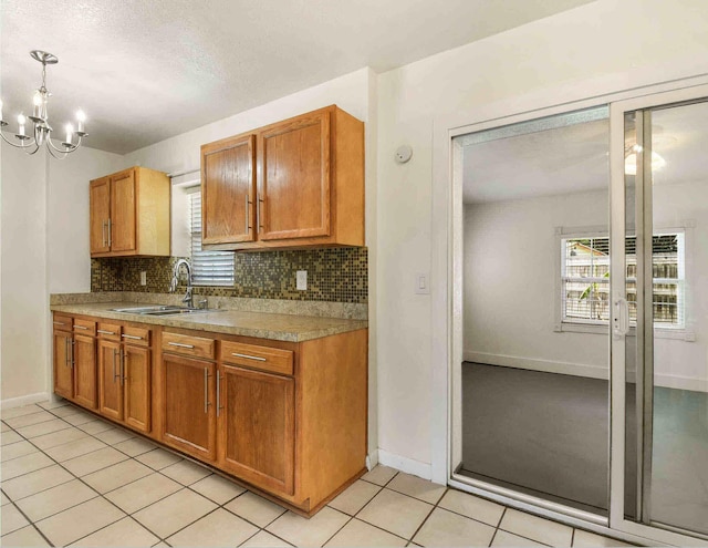 kitchen featuring an inviting chandelier, sink, decorative backsplash, decorative light fixtures, and light tile patterned flooring