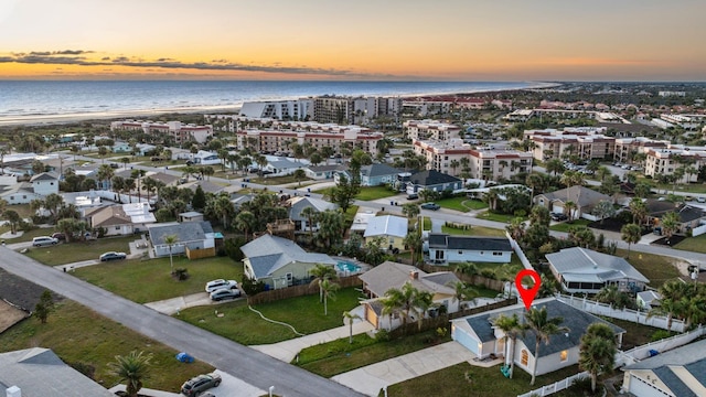 aerial view at dusk with a water view and a view of the beach