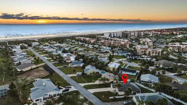 aerial view at dusk with a water view and a view of the beach