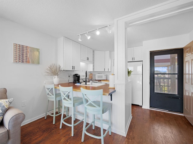 4250 S A1A Unit D33, Saint Augustine, FL 32080 - kitchen featuring white appliances, a sink, baseboards, dark wood-type flooring, and a textured ceiling