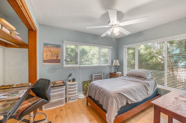 bedroom featuring ceiling fan, light hardwood / wood-style flooring, and multiple windows