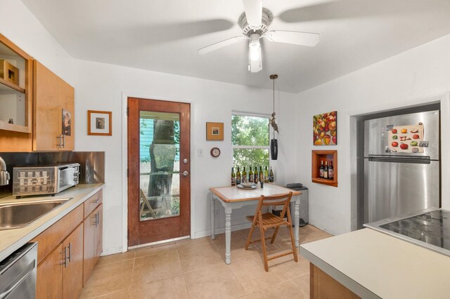 kitchen featuring ceiling fan, sink, hanging light fixtures, stainless steel appliances, and light tile patterned floors