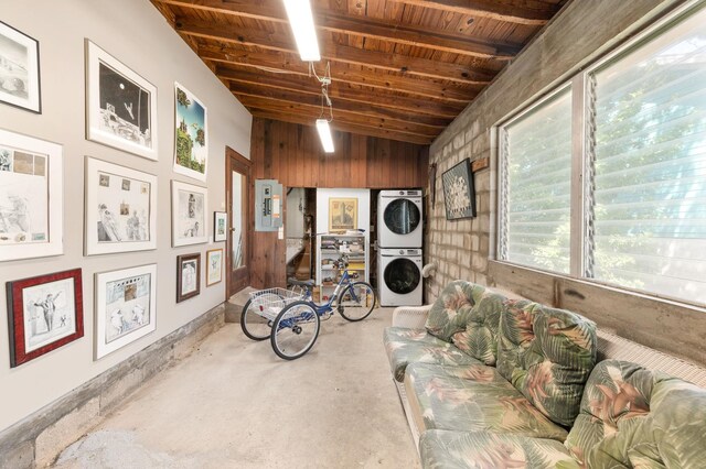 interior space with concrete floors, stacked washing maching and dryer, wood ceiling, and electric panel