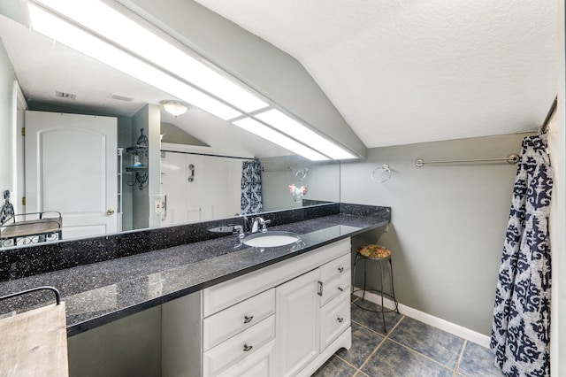 bathroom featuring vanity, tile patterned flooring, vaulted ceiling, and a textured ceiling