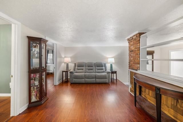 living room featuring dark wood-type flooring and a textured ceiling